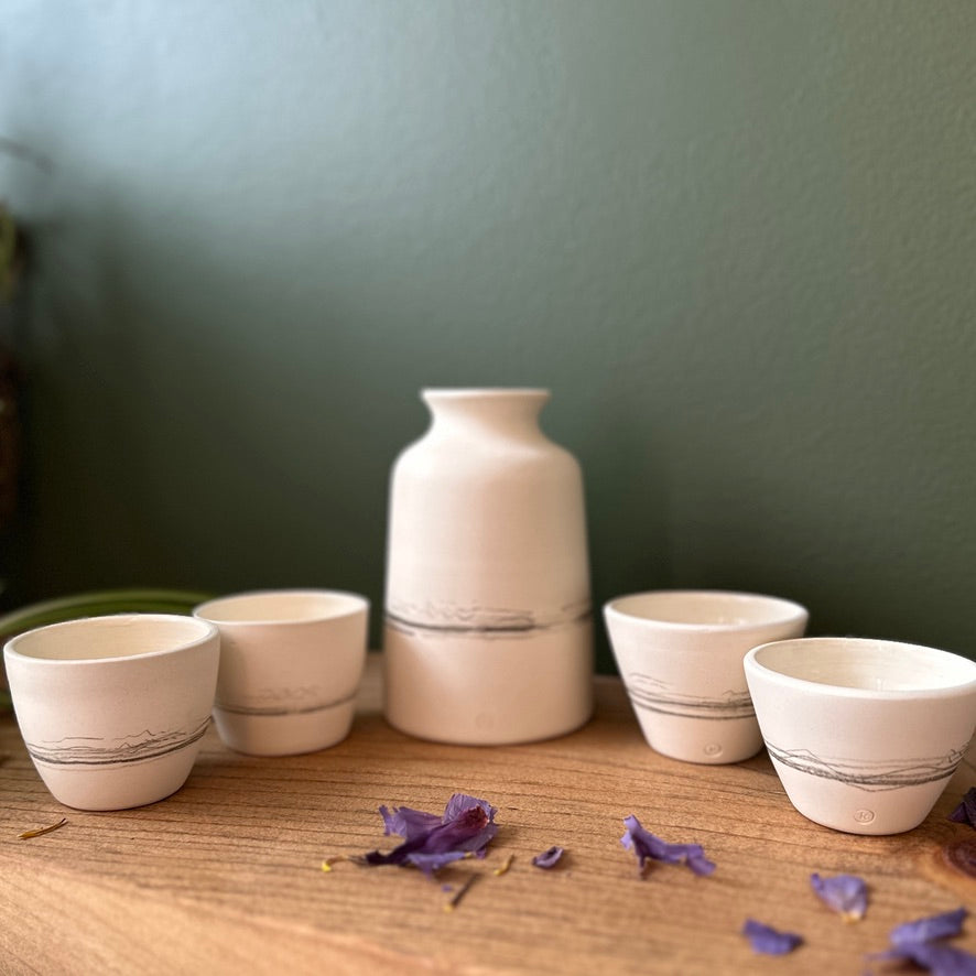 Set of ceramic bowls and a vase on a wooden surface with a green wall background